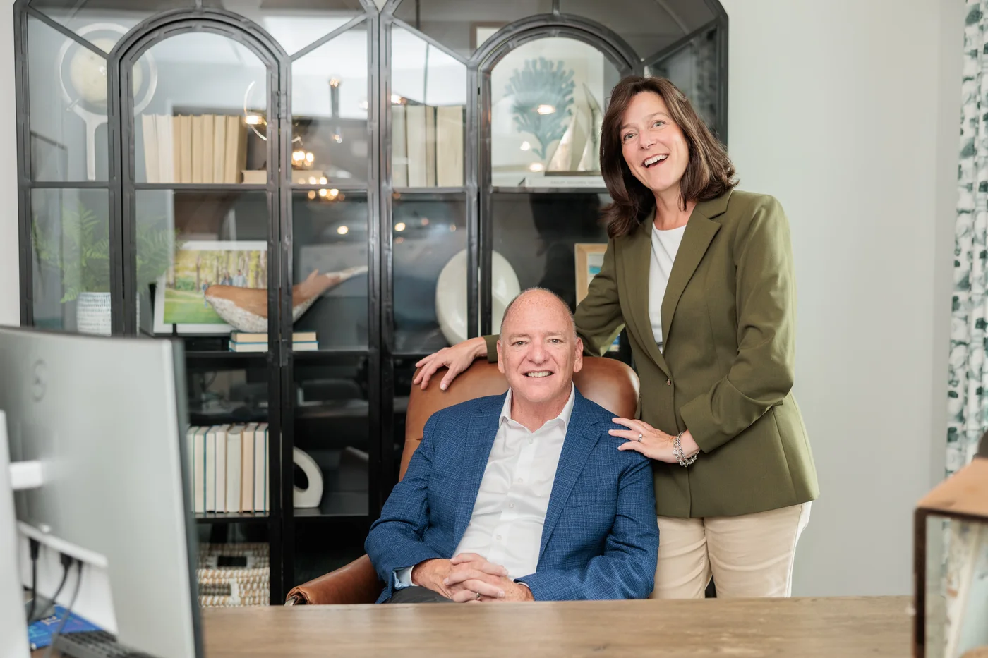 Buddy Blake smiles from an office chair beside a standing woman.