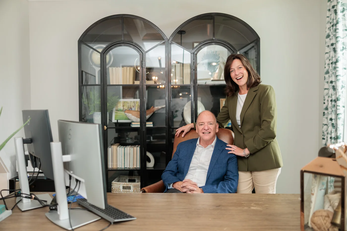 Buddy Blake poses with a woman behind a desk with two monitors.