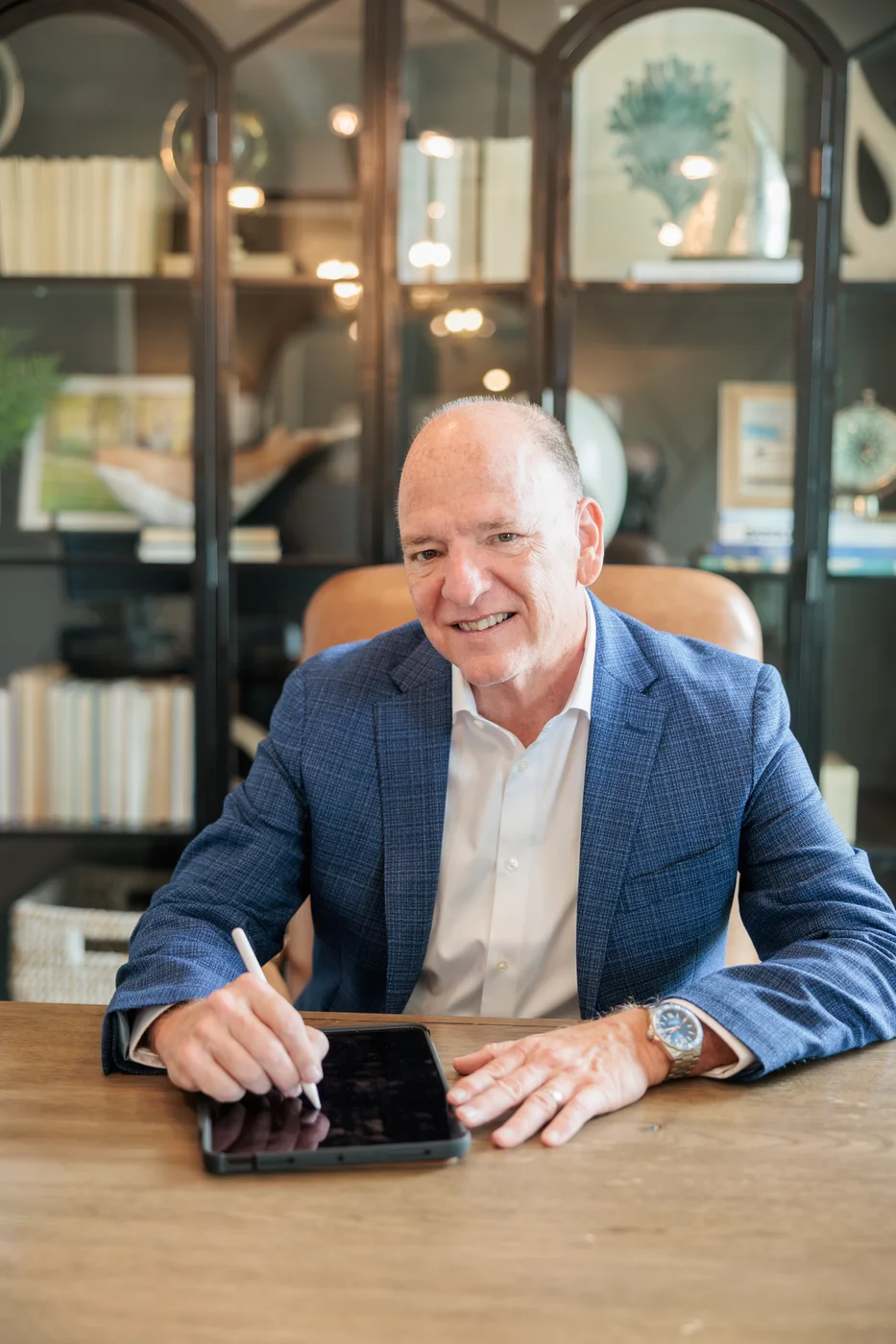 Buddy Blake smiles while working on a tablet at his desk.